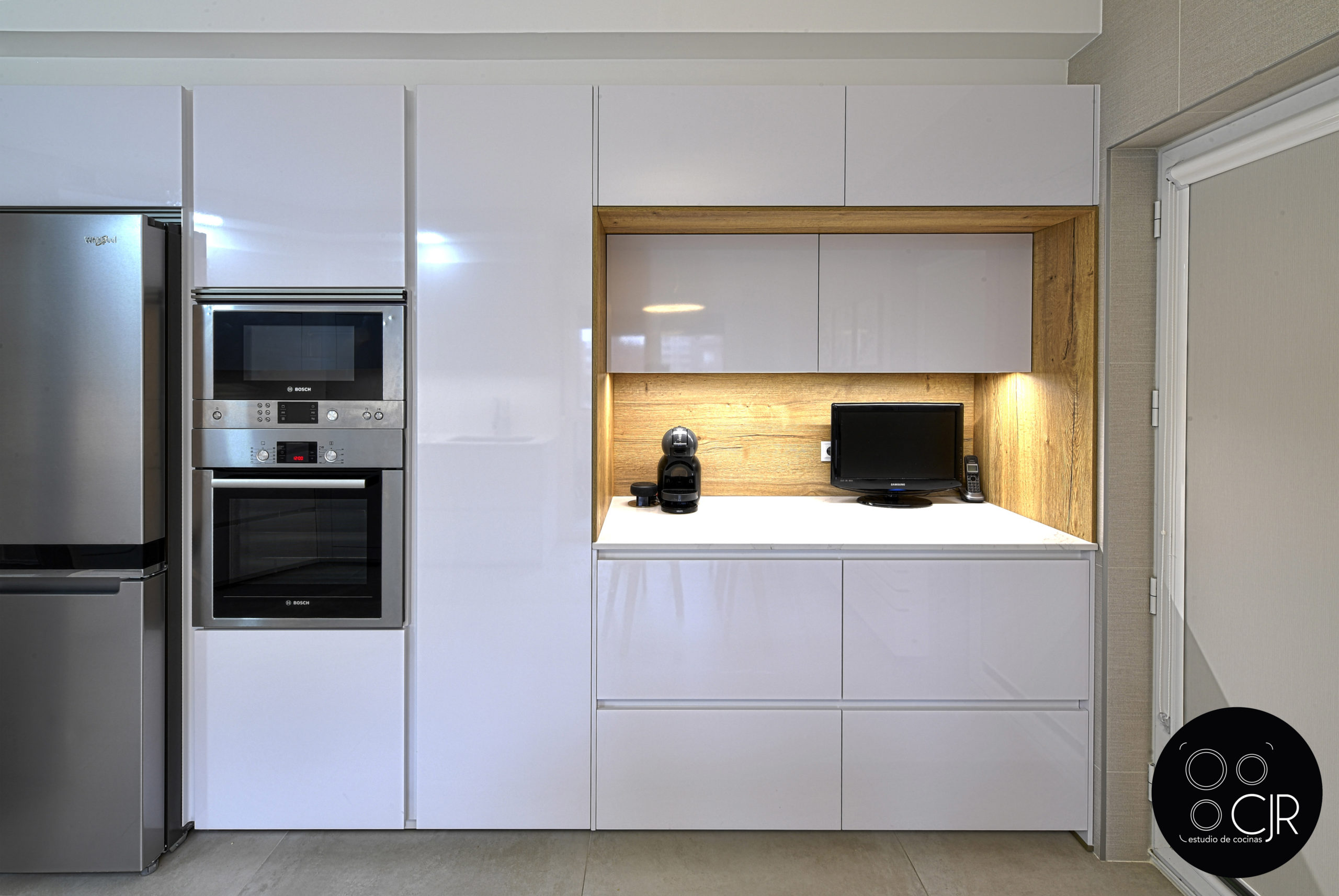 Vista frontal de cocina en blanco y madera con electrodomésticos