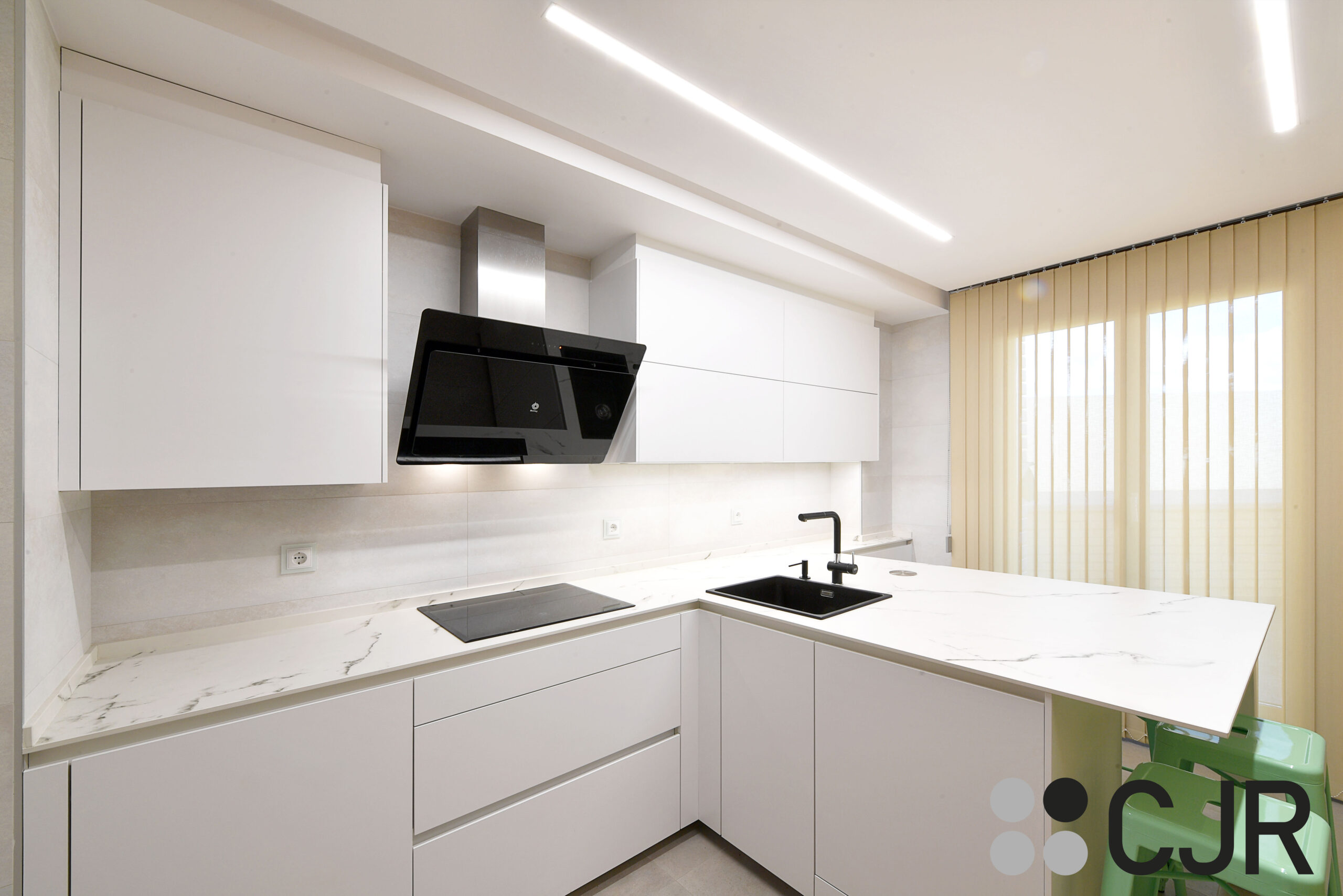 cocina madera y blanca con electrodomesticos en negro y sillas en verde cjr