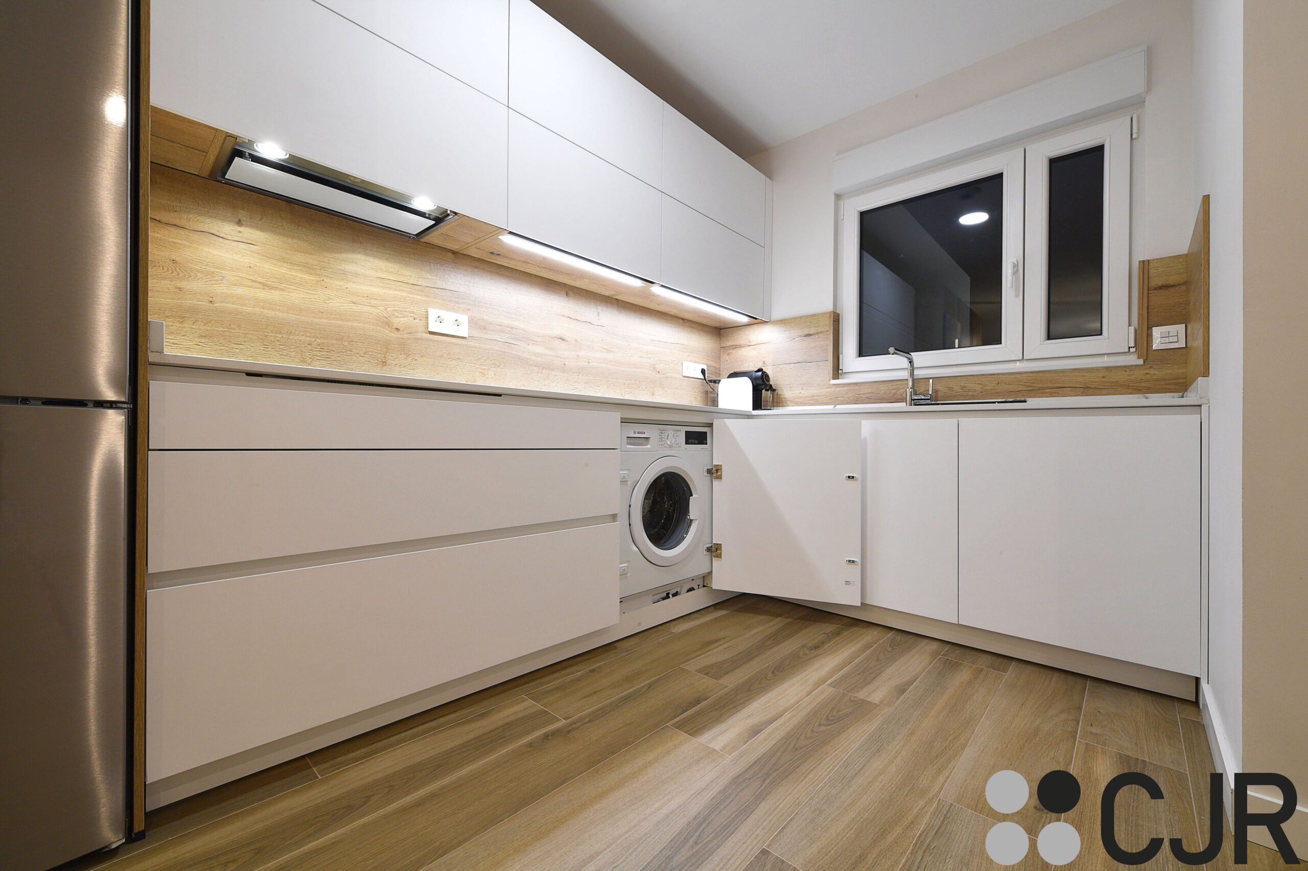 lavadora integrada en cocina madera y blanca abierta al salon cjr