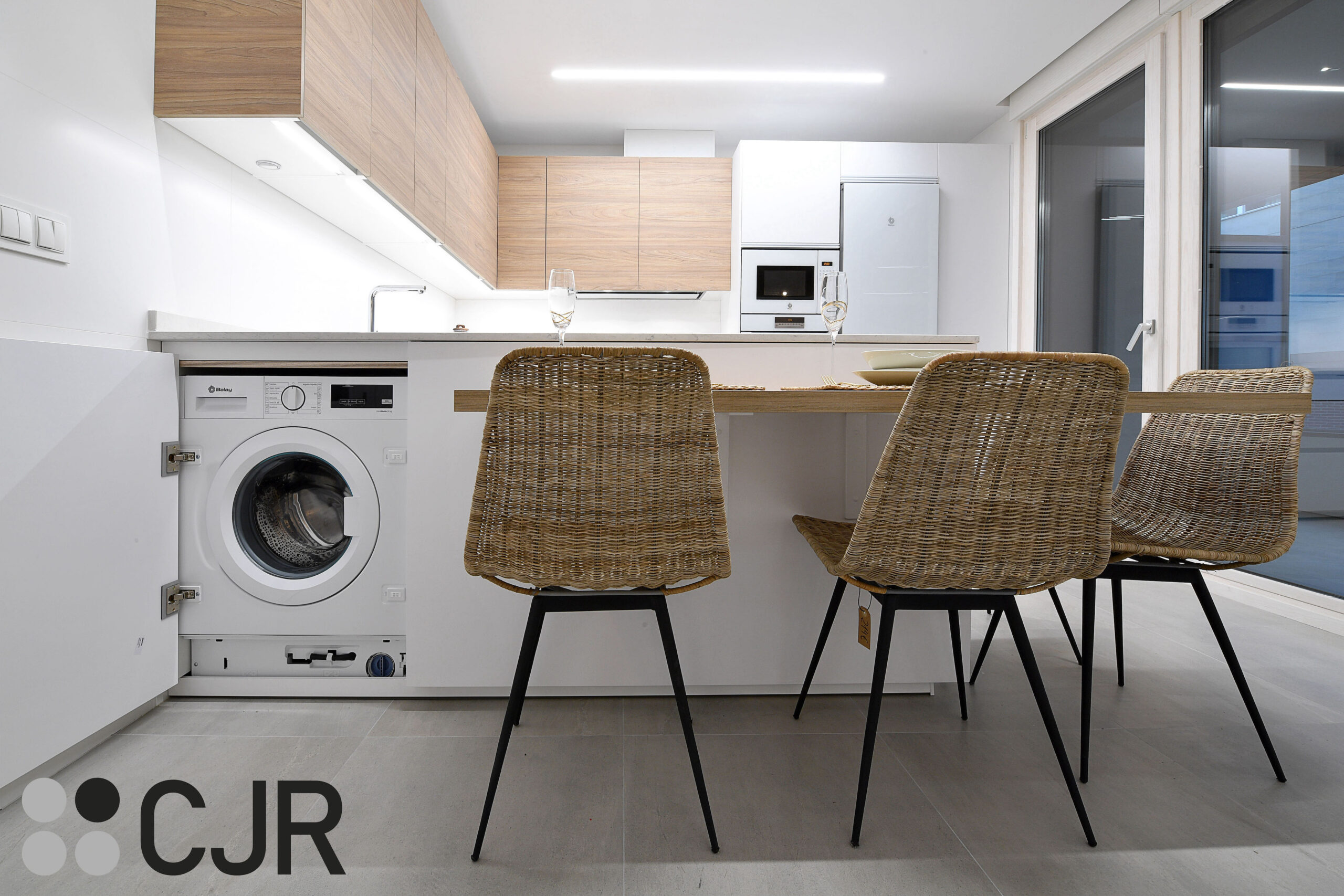 lavadora integrada en la cocina blanca mate y madera semiabierta al salon cjr