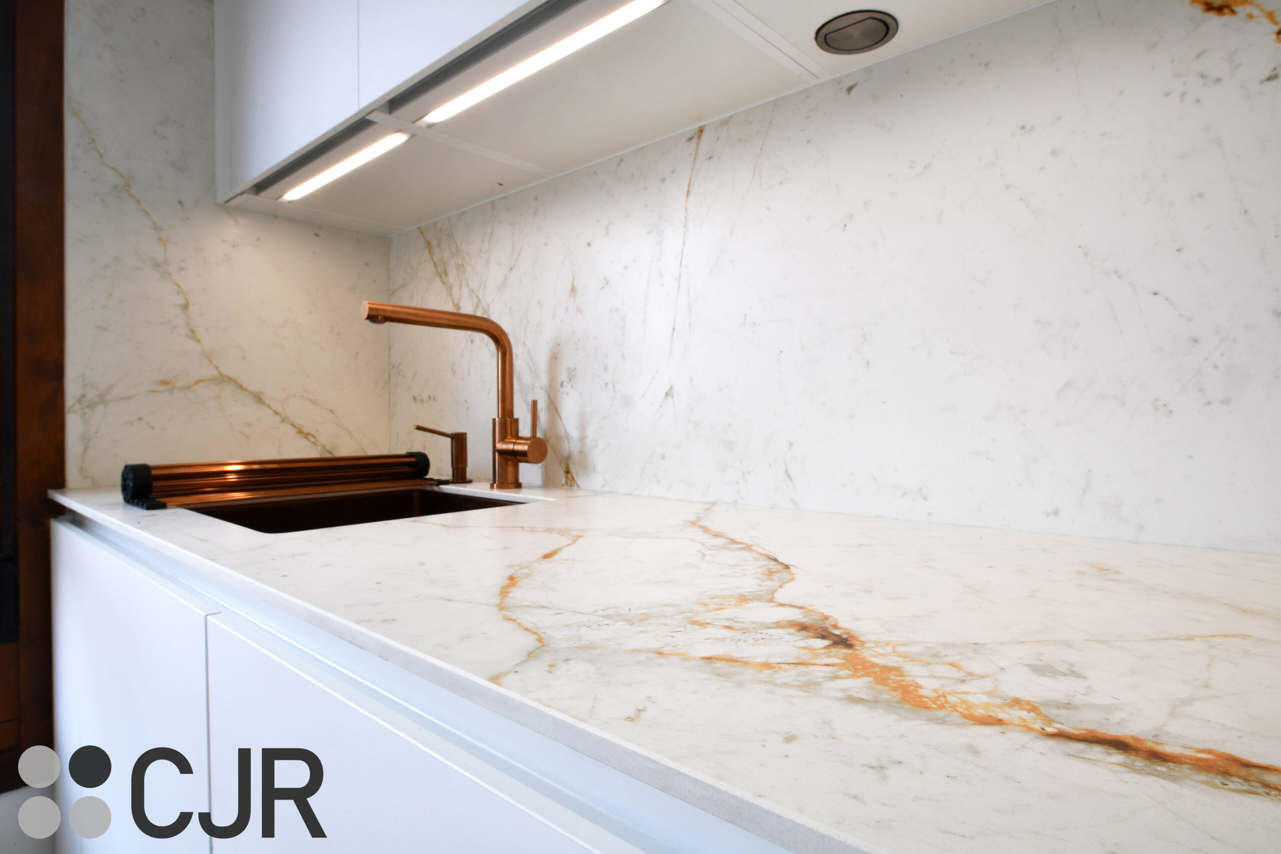 encimera neolith abu dhabi en cocina blanca con grifo cobre cjr