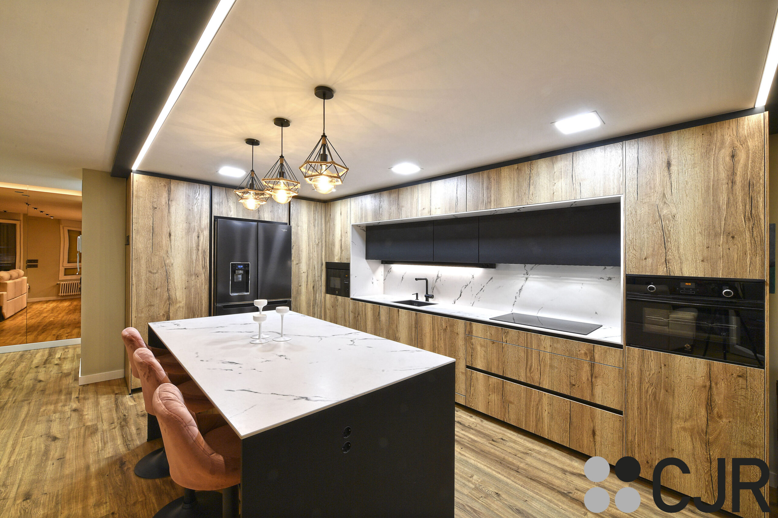 cocina abierta al salon con isla negra mate madera y dekton kairos cjr