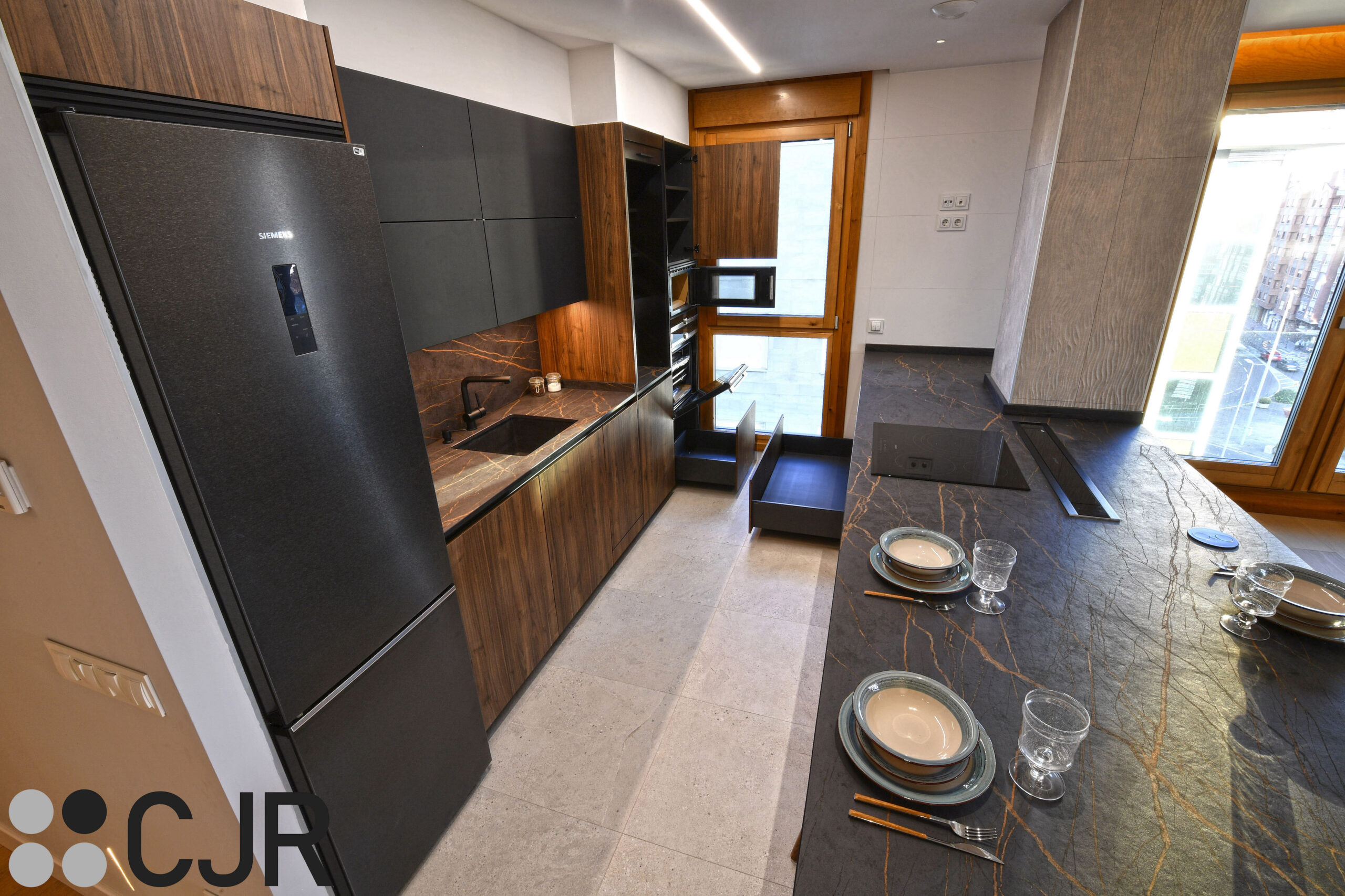 cocina abierta al salon con muebles bajos en negro y madera cocinas cjr