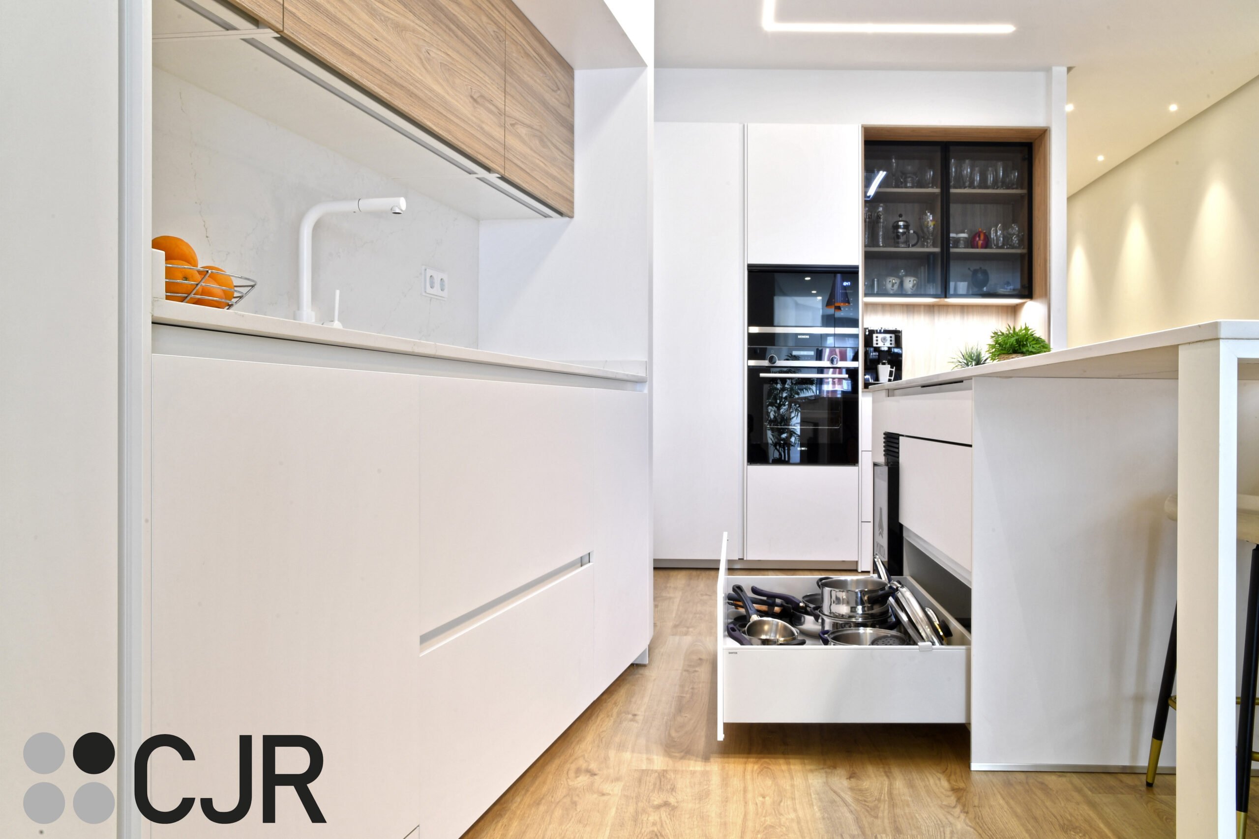mueble bajo en isla de cocina blanca y madera abierta al salon con isla Cocinas CJR
