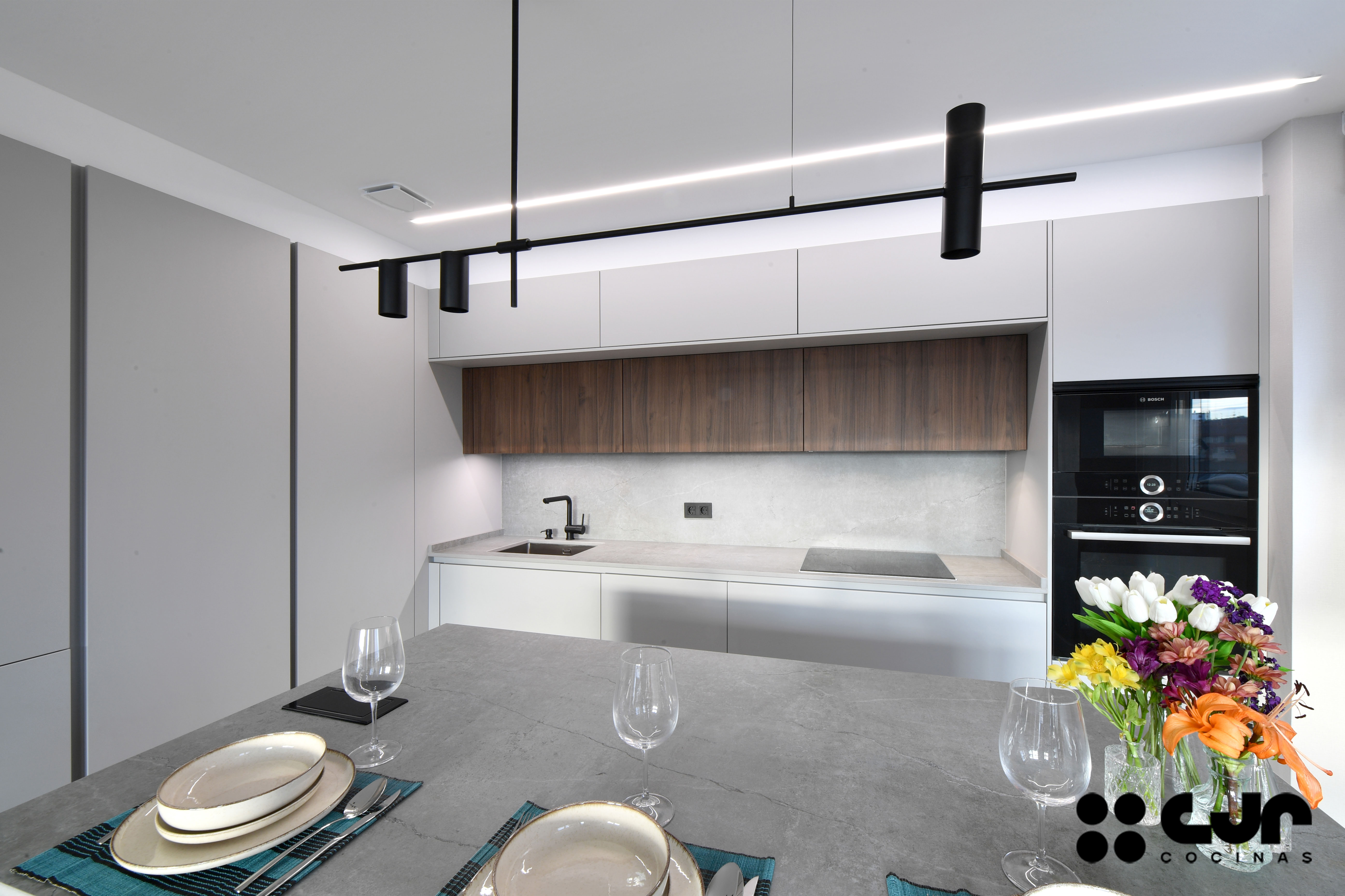 cocina abierta con isla gris y madera cocinas cjr