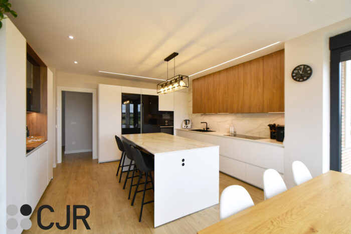 Cocina moderna blanca y madera con isla central y mesa Cocinas CJR