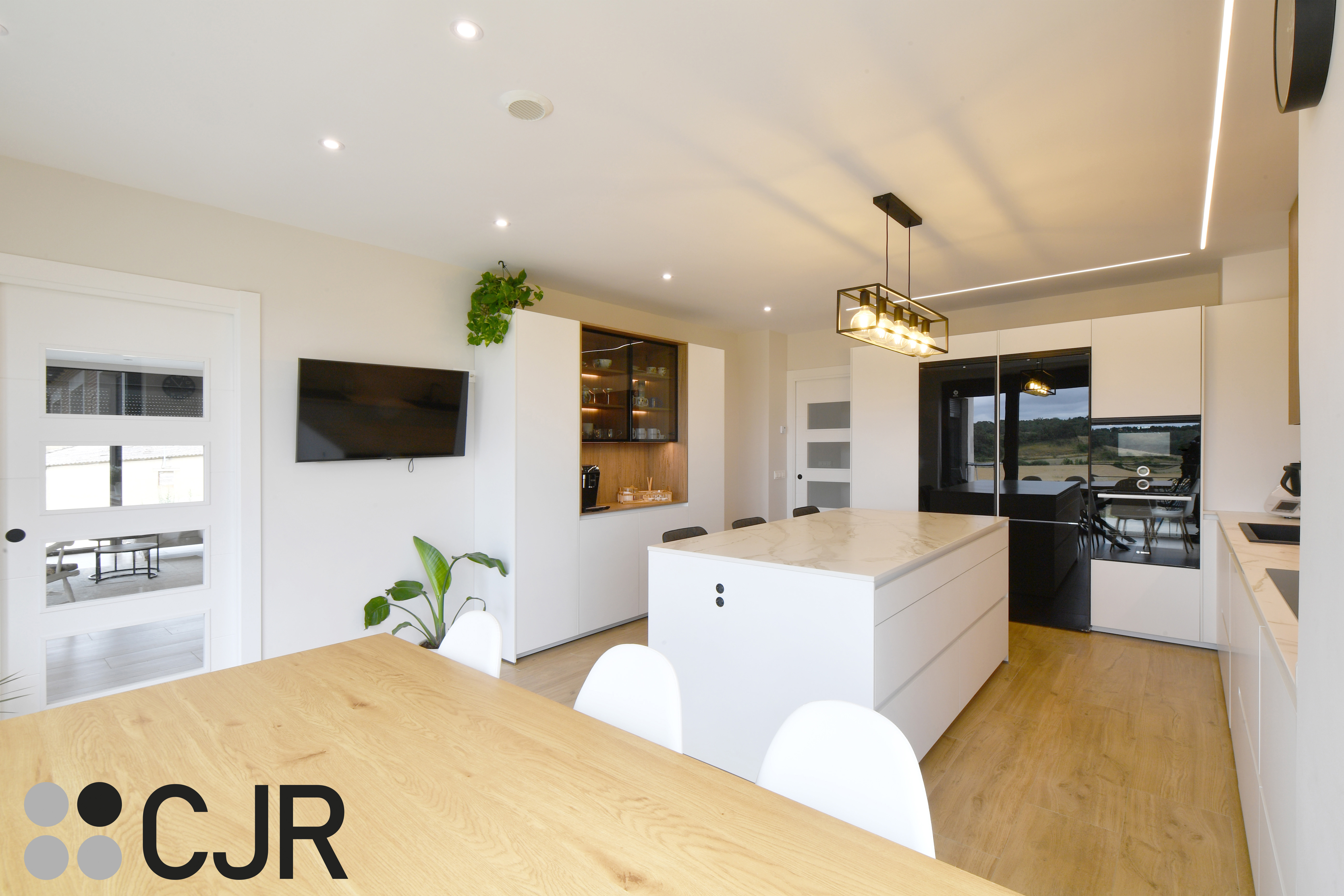 Cocina moderna blanca y madera con isla central y mesa Cocinas CJR