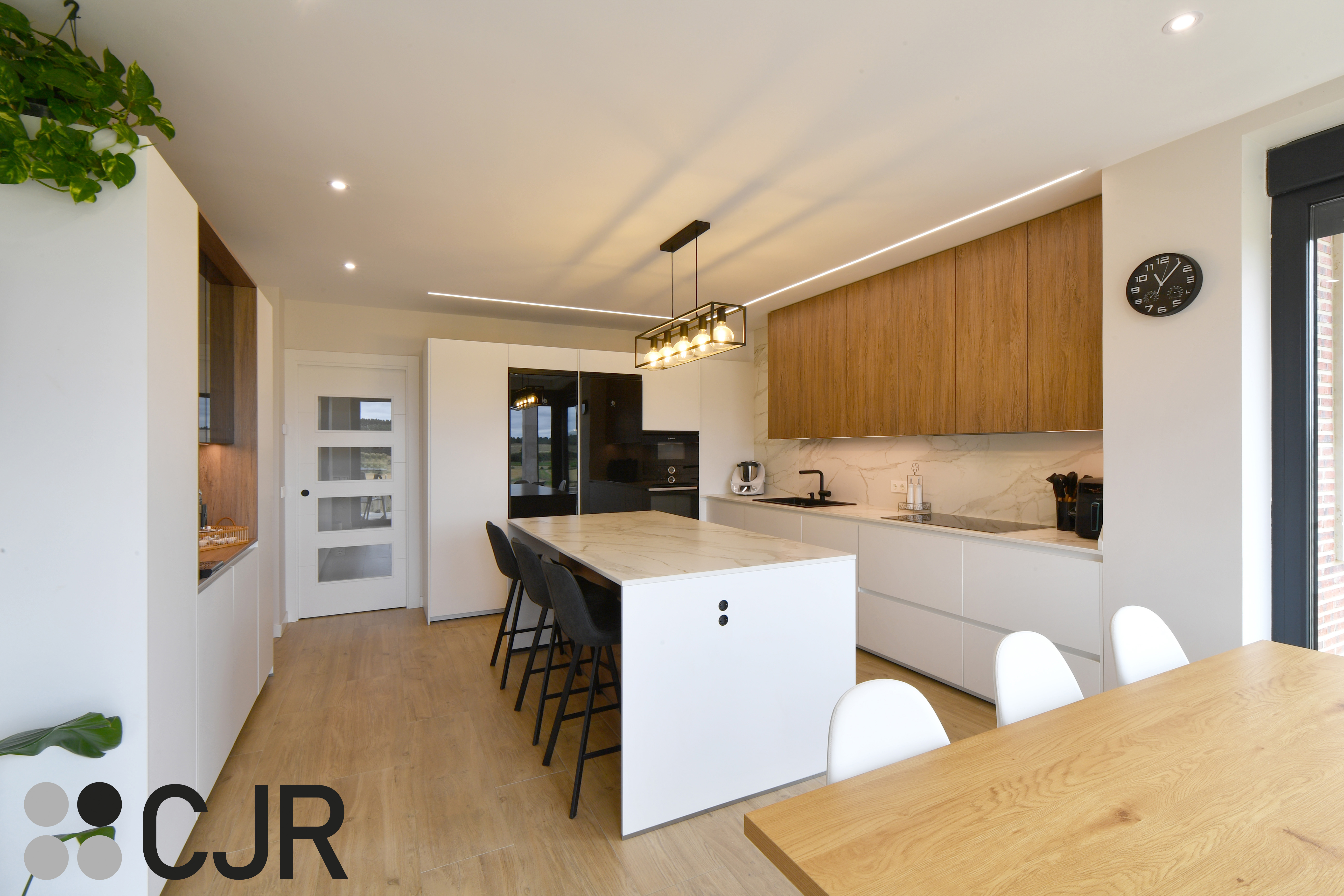 Cocina moderna blanca y madera con isla central y mesa Cocinas CJR