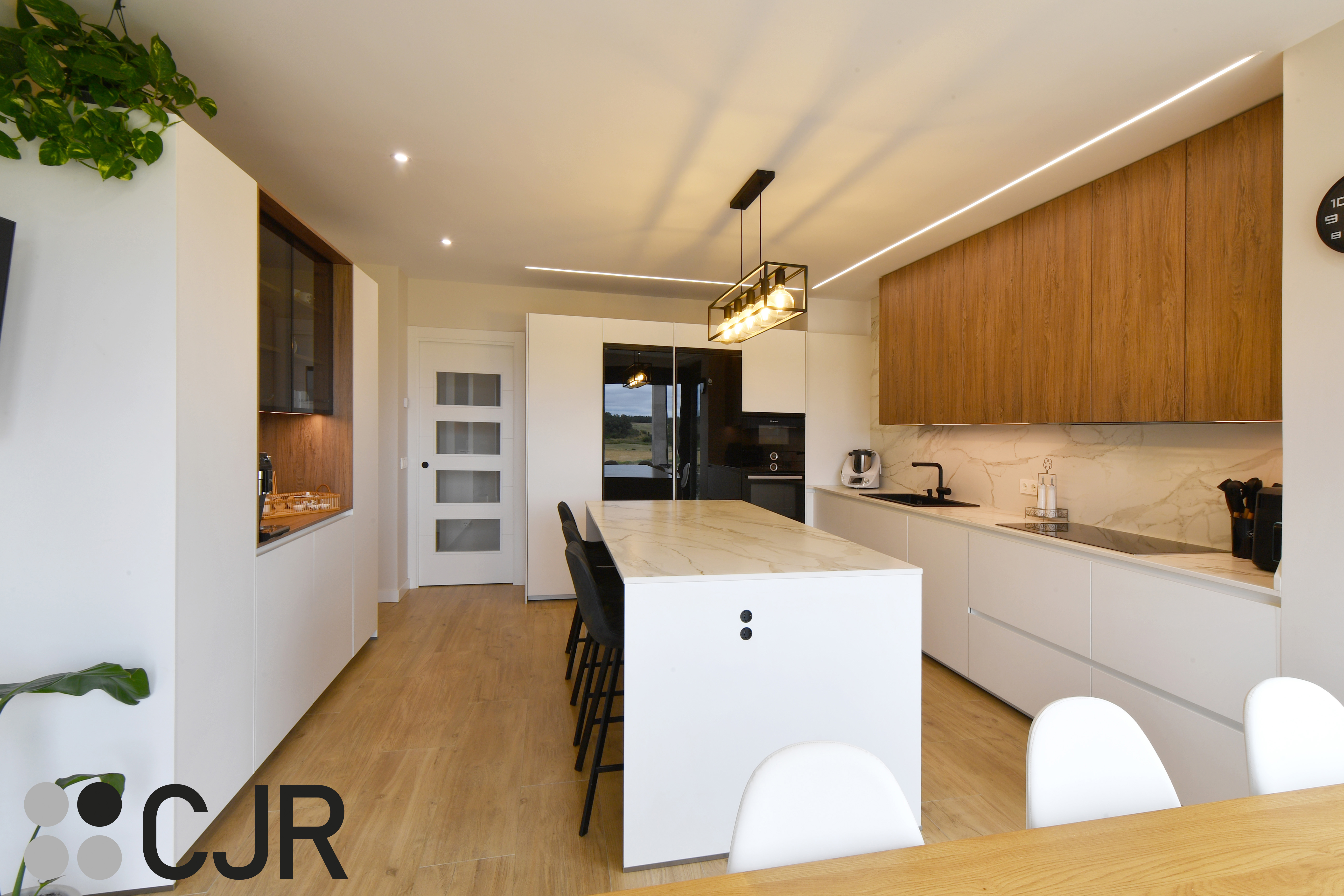Cocina moderna blanca y madera con isla central y mesa Cocinas CJR
