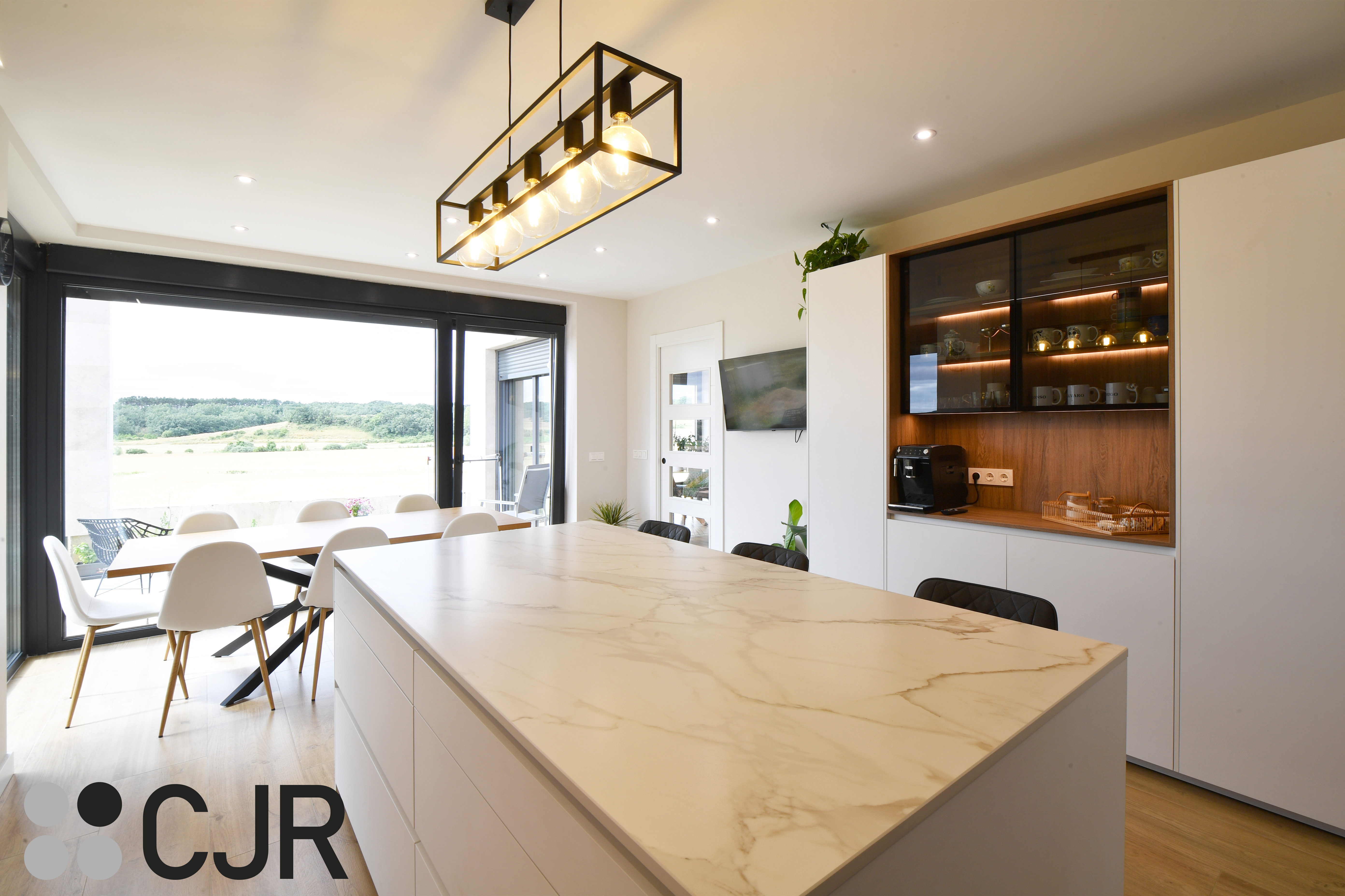 Cocina moderna blanca y madera con isla central y mesa Cocinas CJR