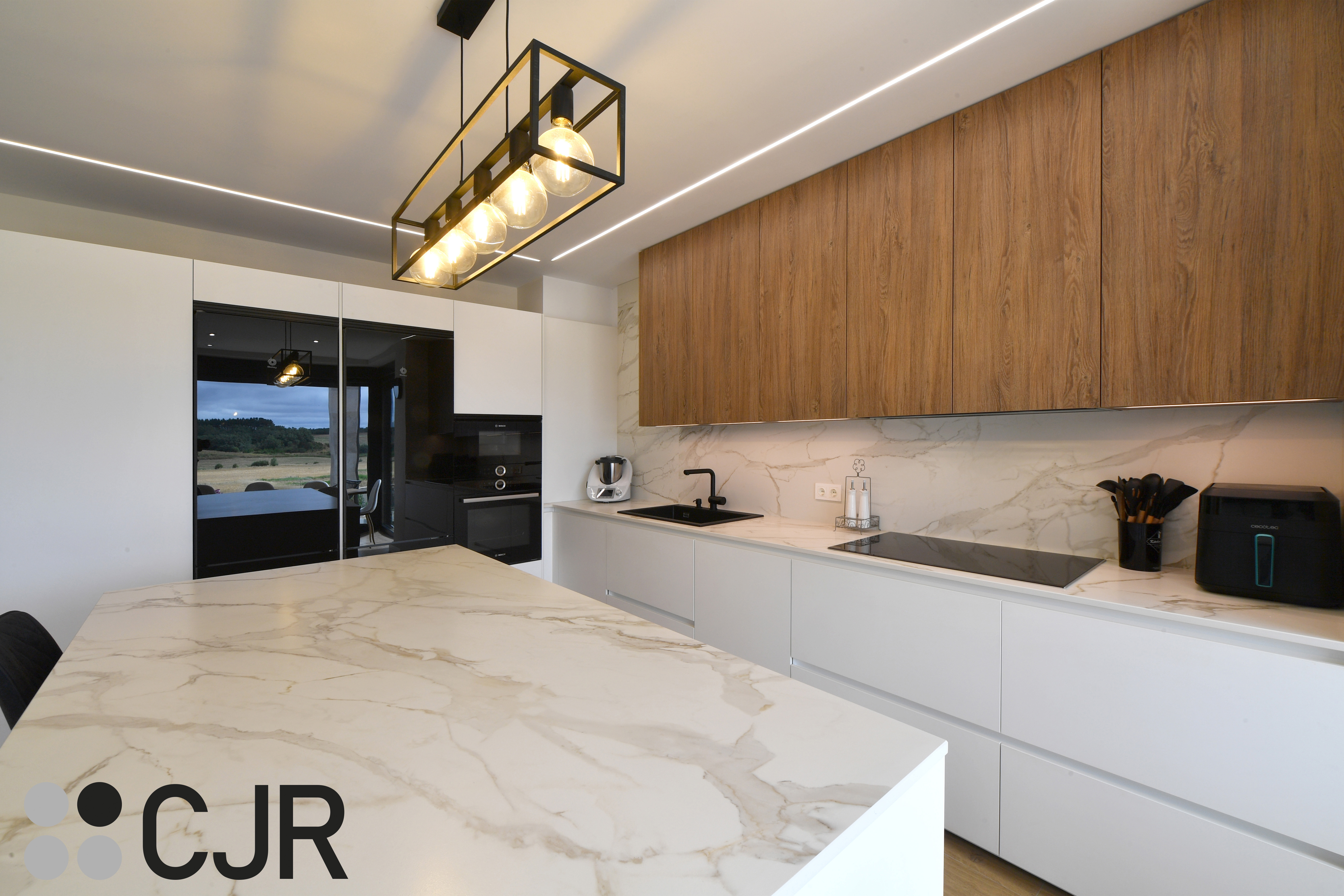 Cocina moderna blanca y madera con isla central y mesa Cocinas CJR