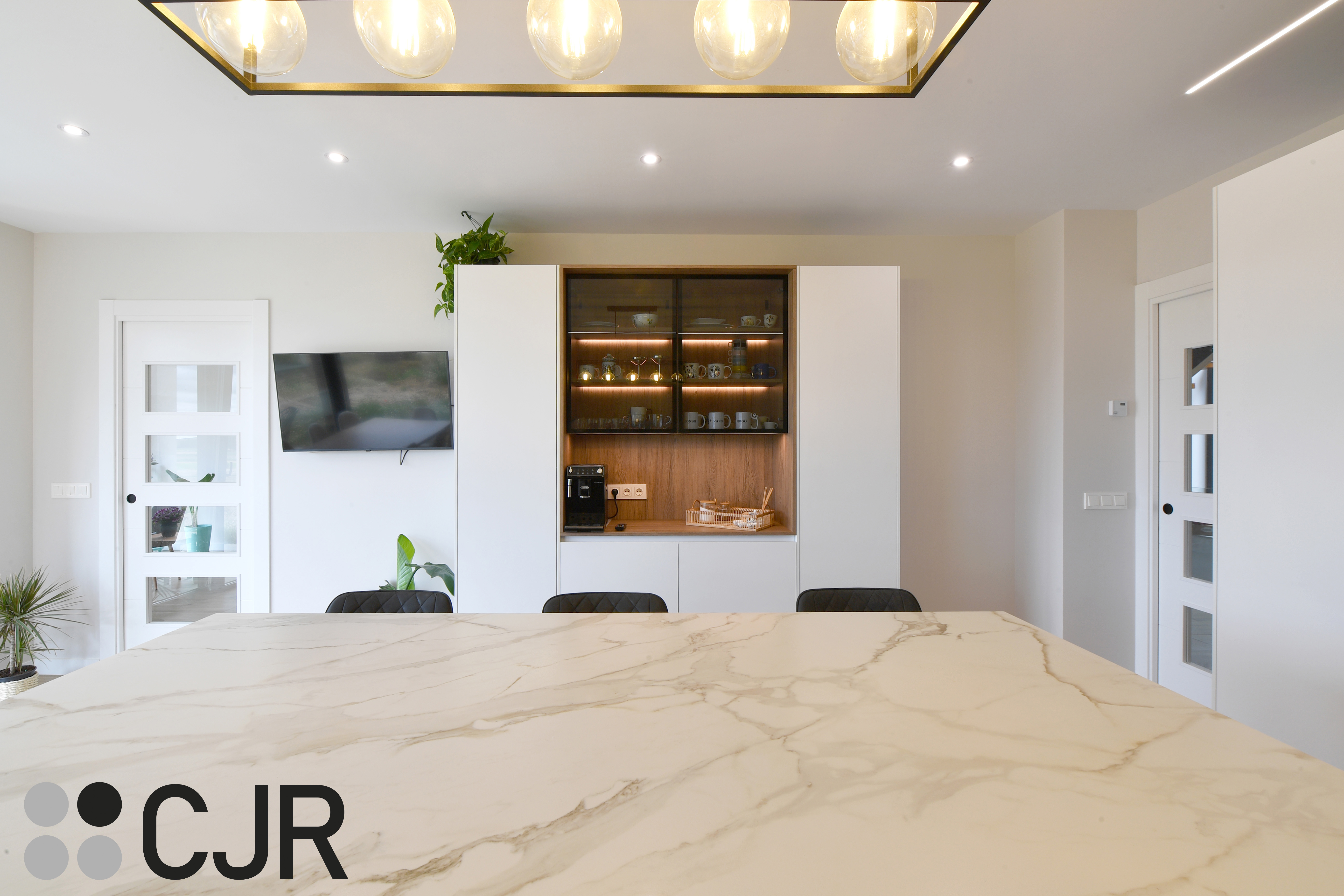 Cocina moderna blanca y madera con isla central y mesa Cocinas CJR