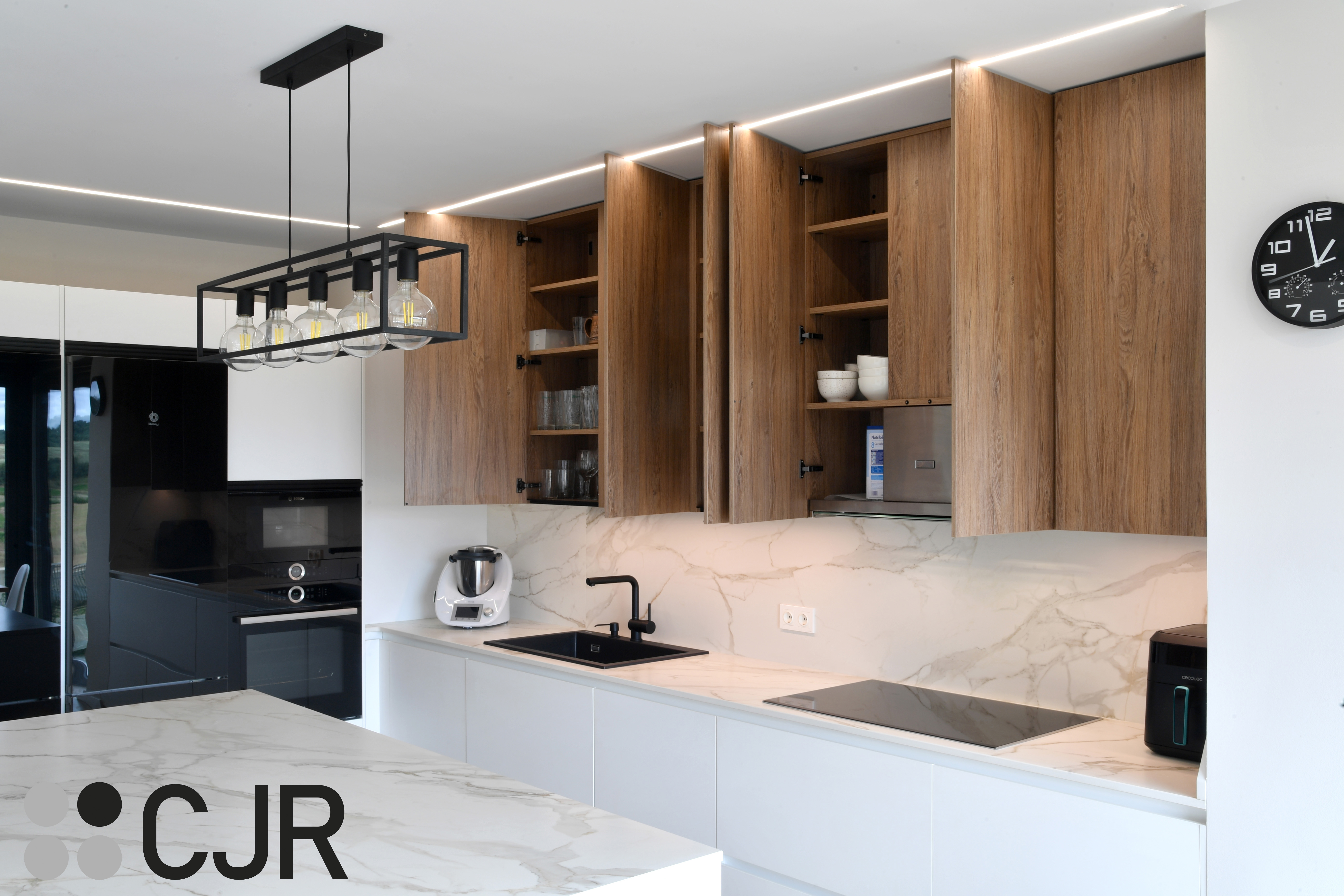 Cocina moderna blanca y madera con isla central y mesa Cocinas CJR