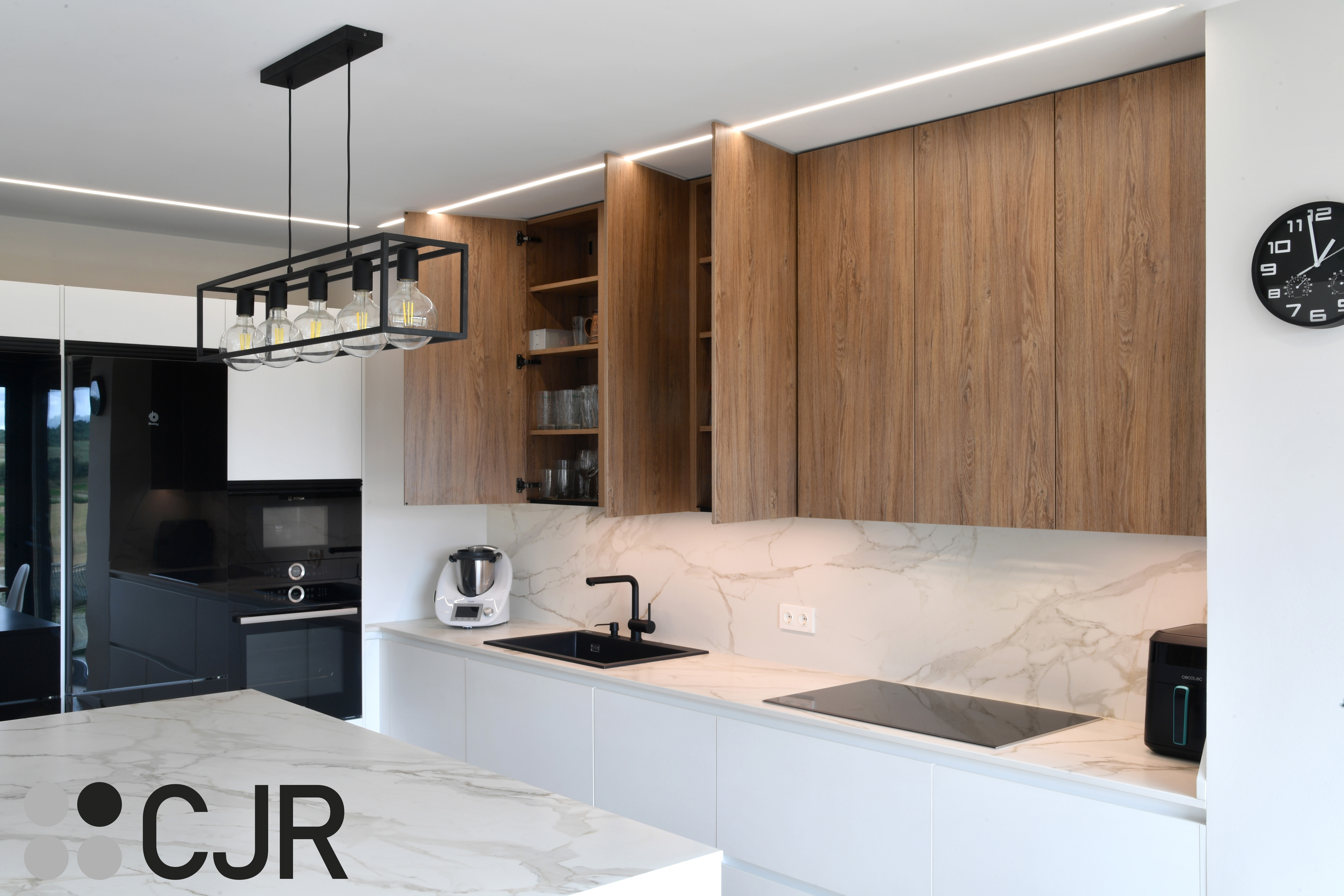 Cocina moderna blanca y madera con isla central y mesa Cocinas CJR