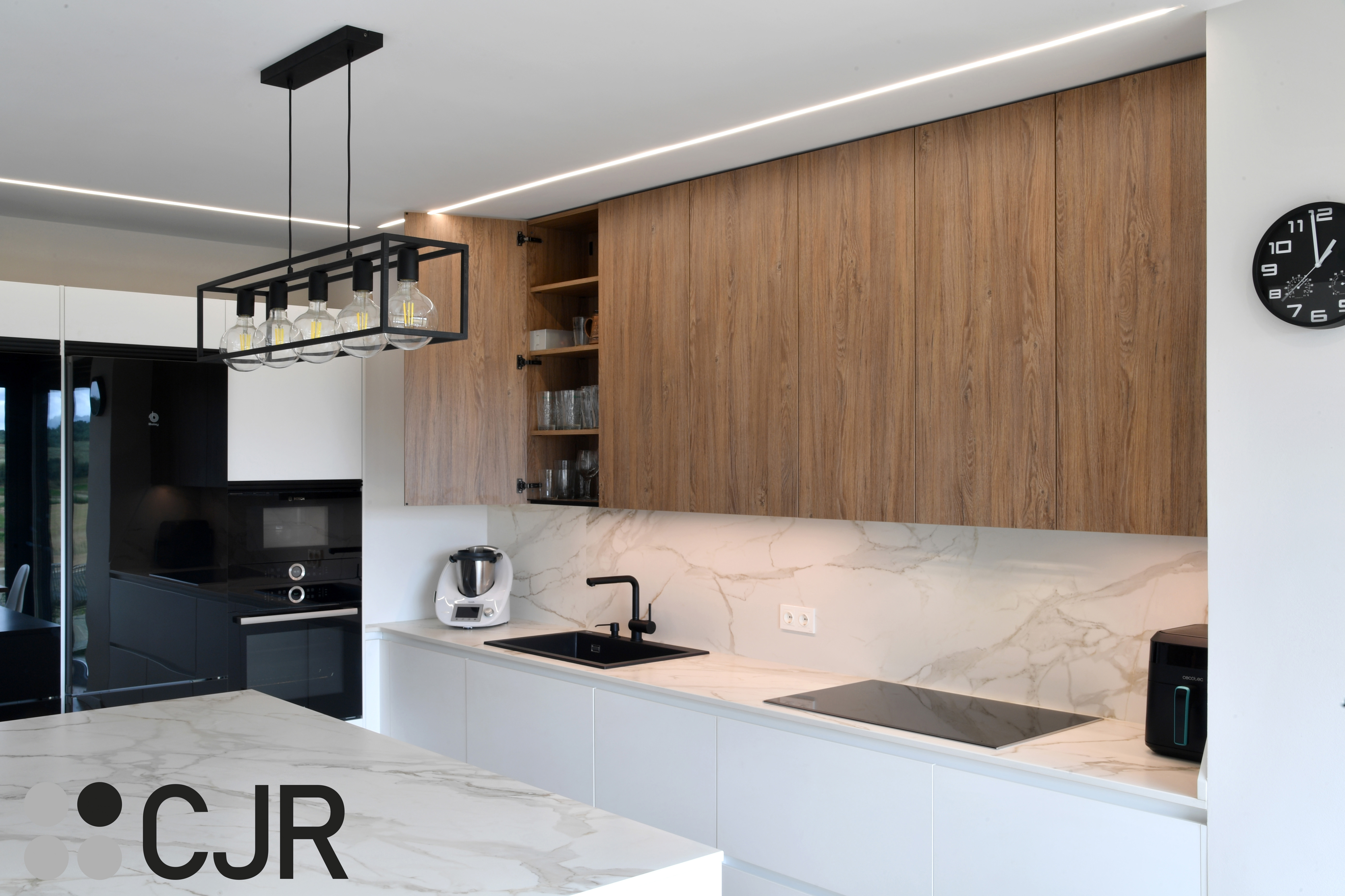 Cocina moderna blanca y madera con isla central y mesa Cocinas CJR