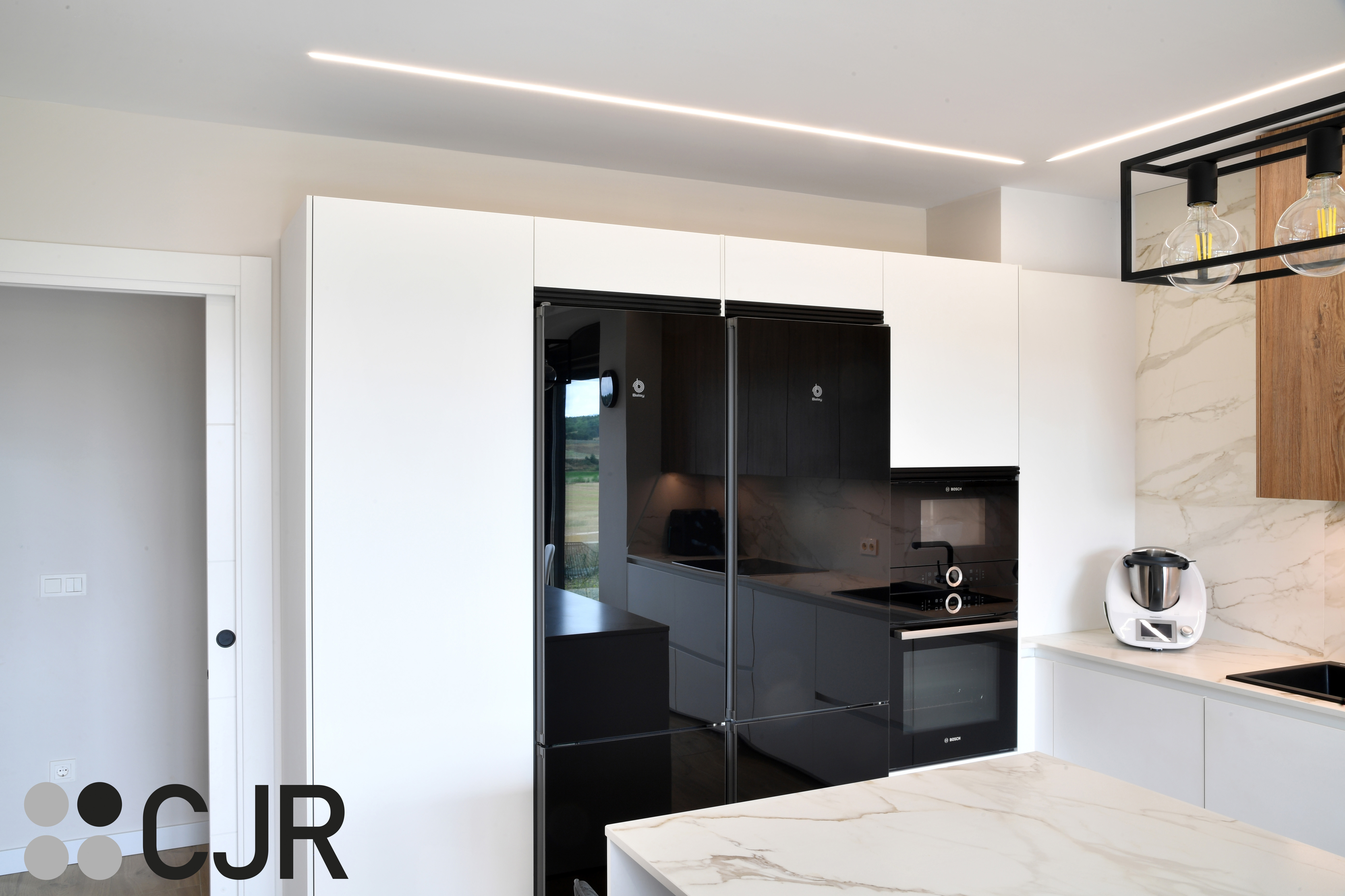 Cocina moderna blanca y madera con isla central y mesa Cocinas CJR