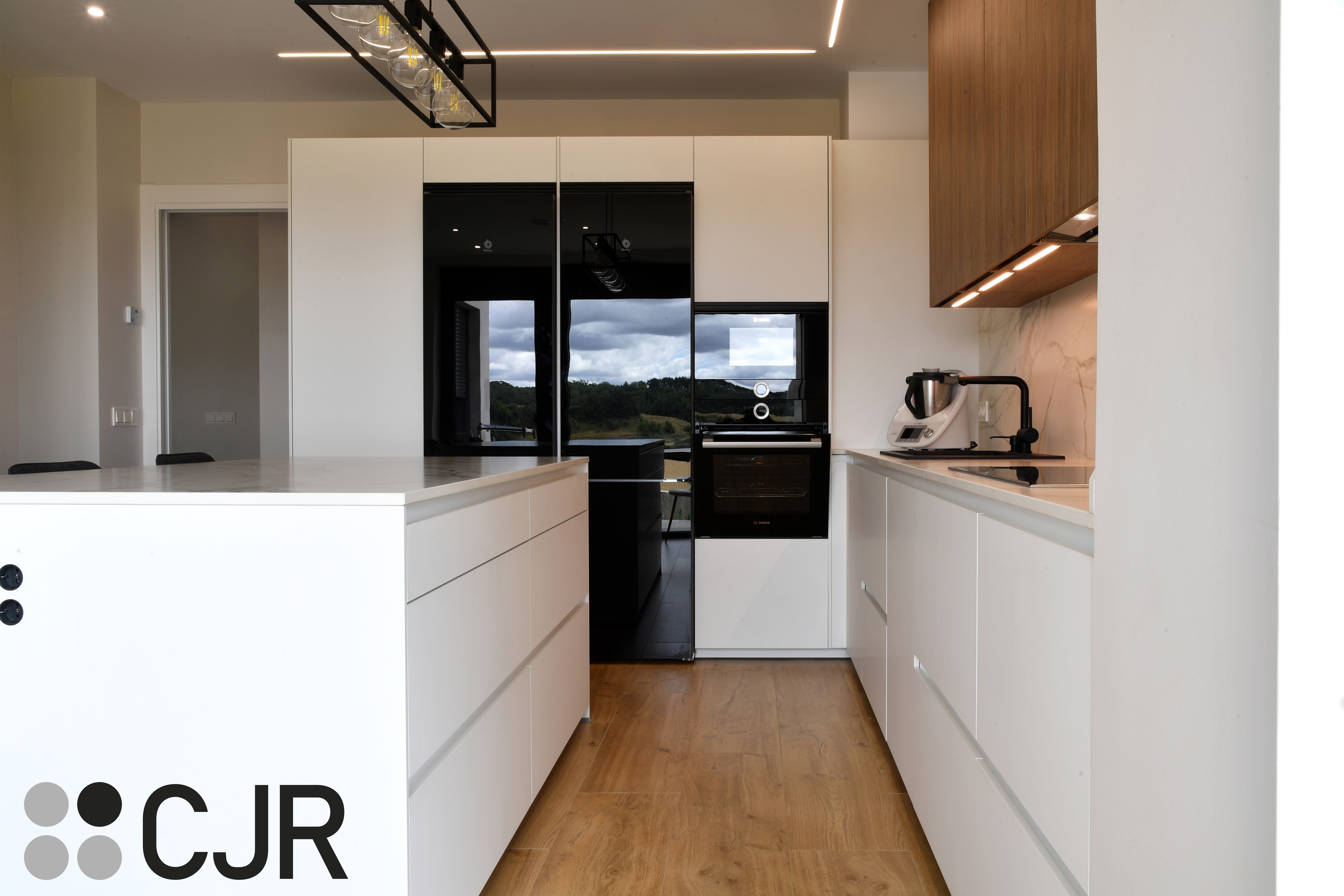 Cocina moderna blanca y madera con isla central y mesa Cocinas CJR