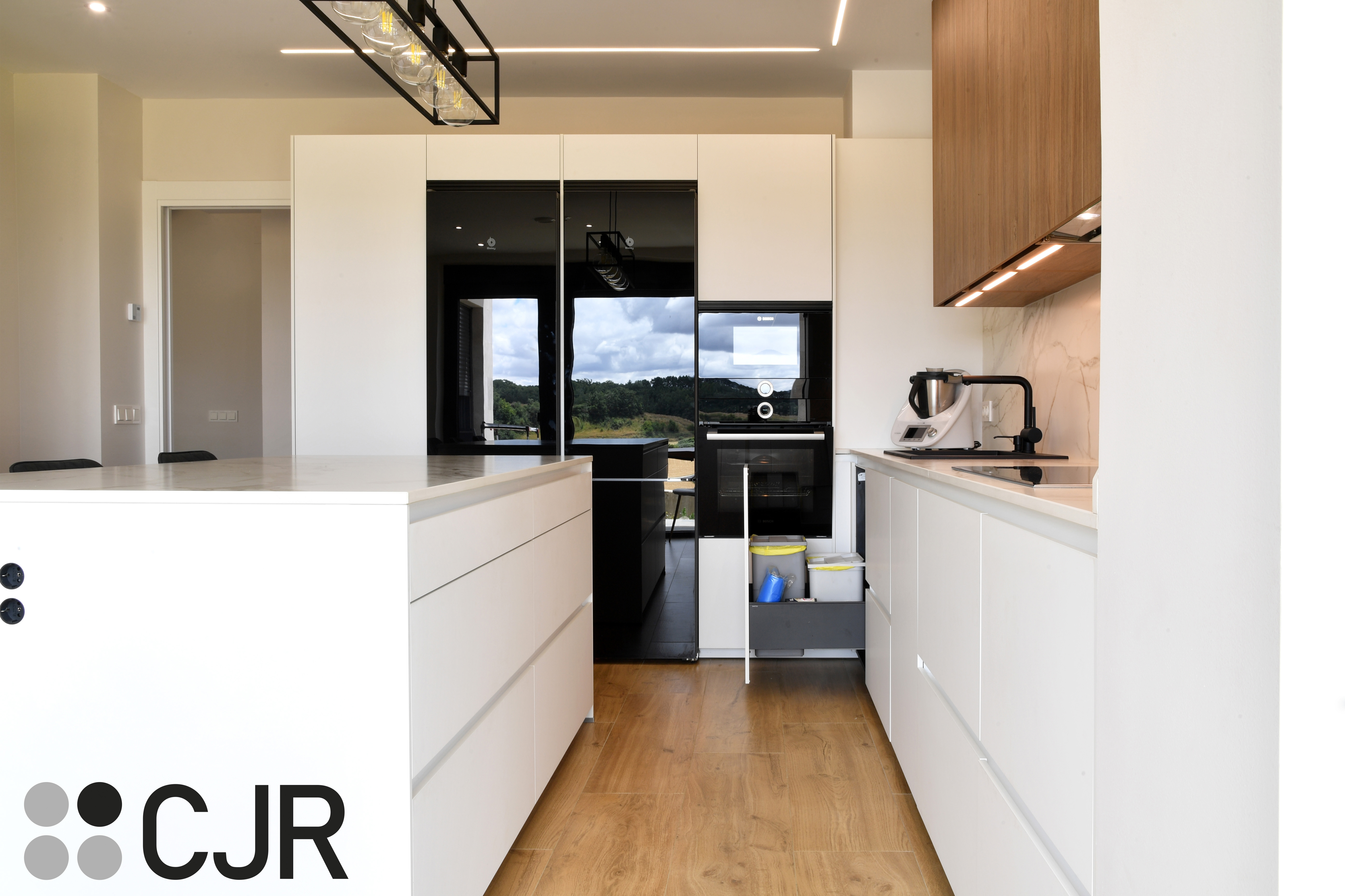 Cocina moderna blanca y madera con isla central y mesa Cocinas CJR