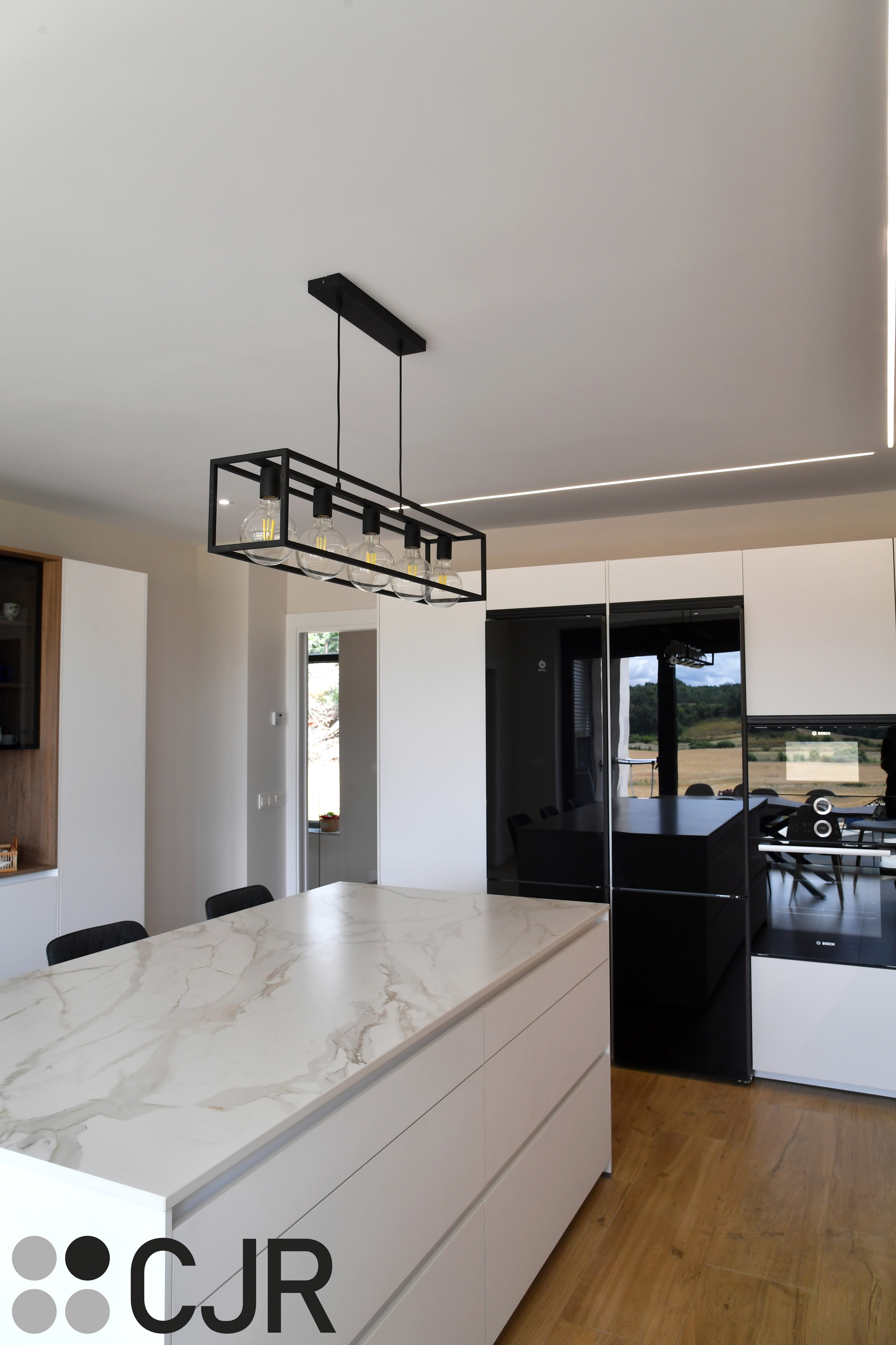 Cocina moderna blanca y madera con isla central y mesa Cocinas CJR