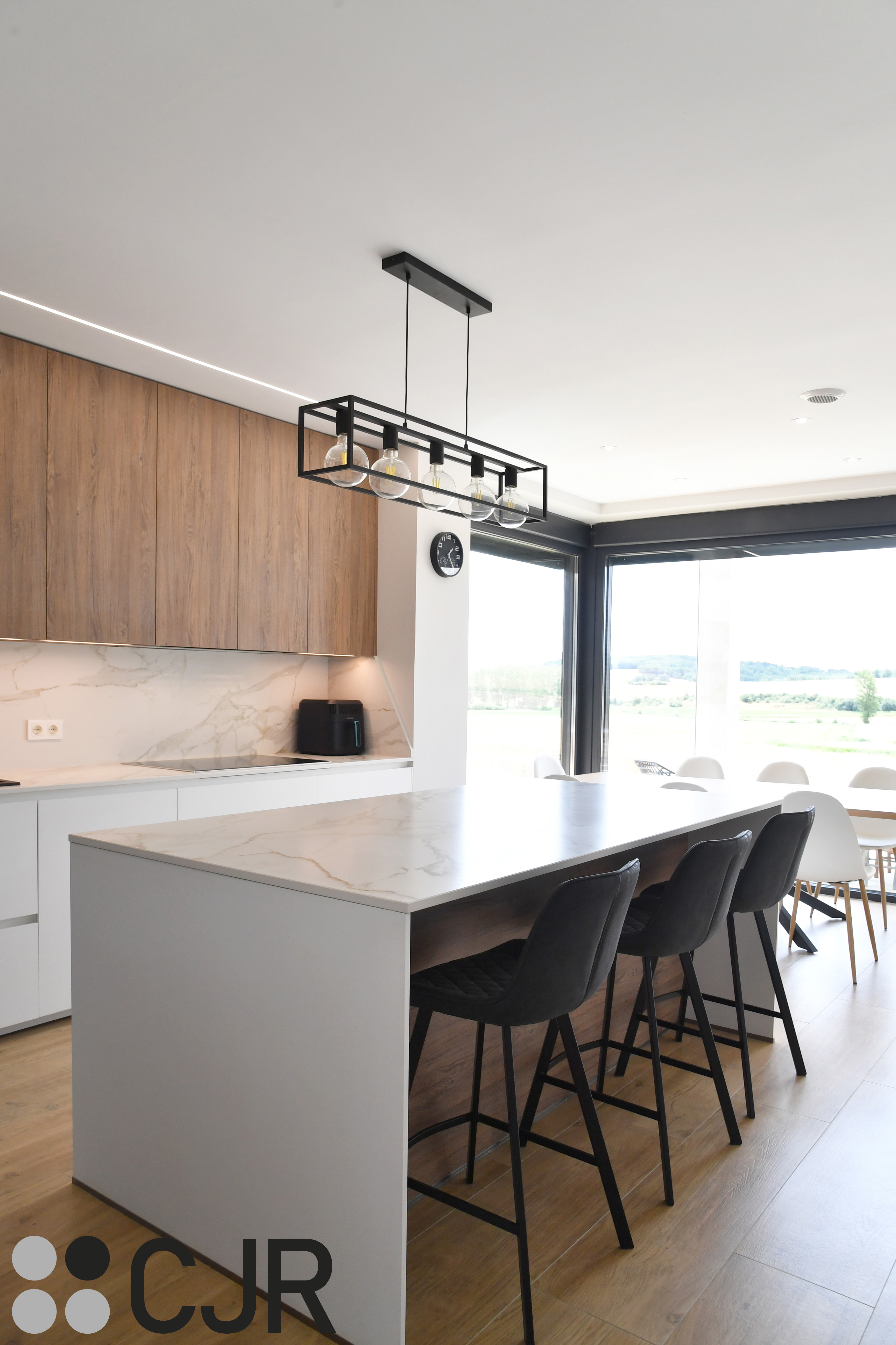 Cocina moderna blanca y madera con isla central y mesa Cocinas CJR