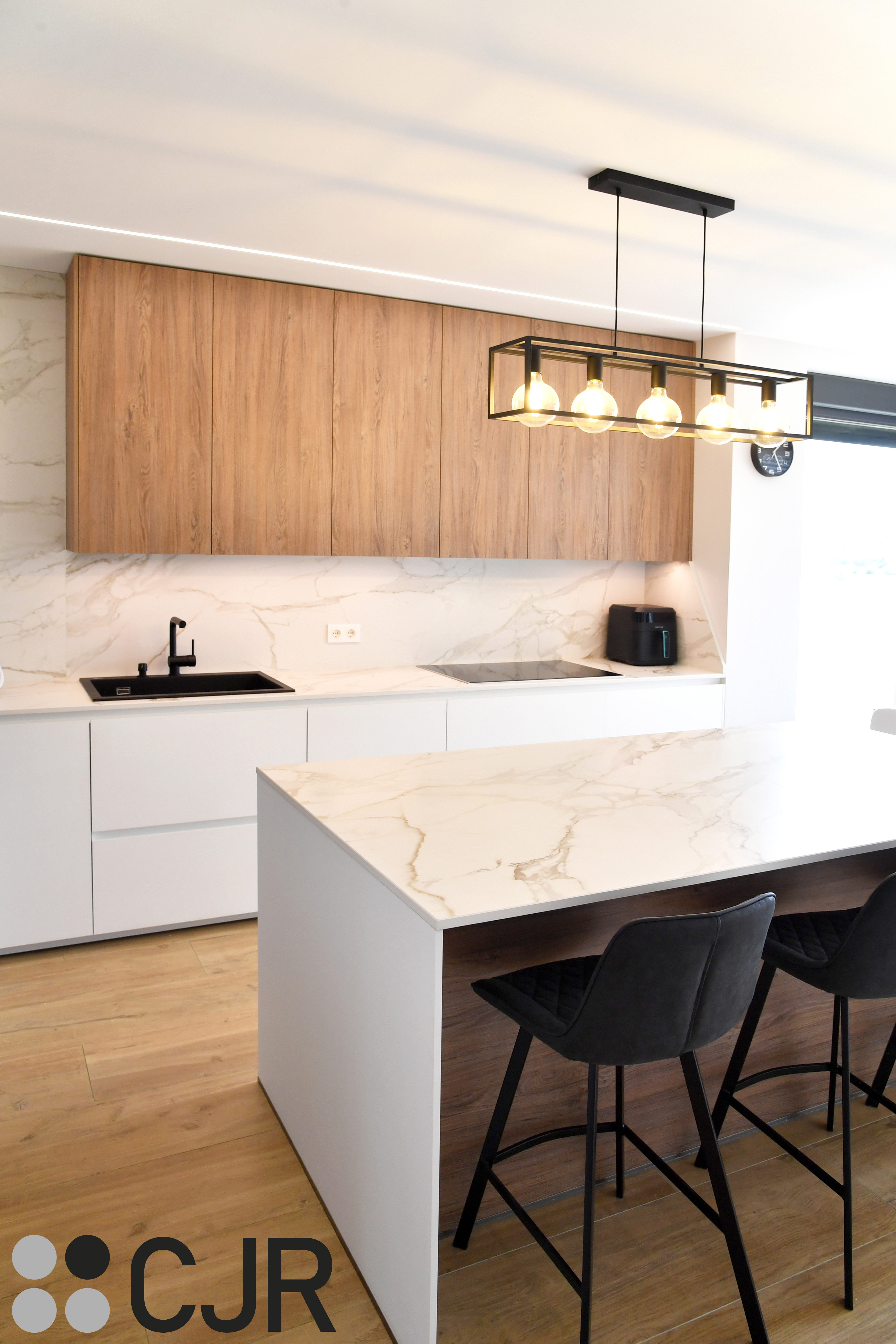 Cocina moderna blanca y madera con isla central y mesa Cocinas CJR